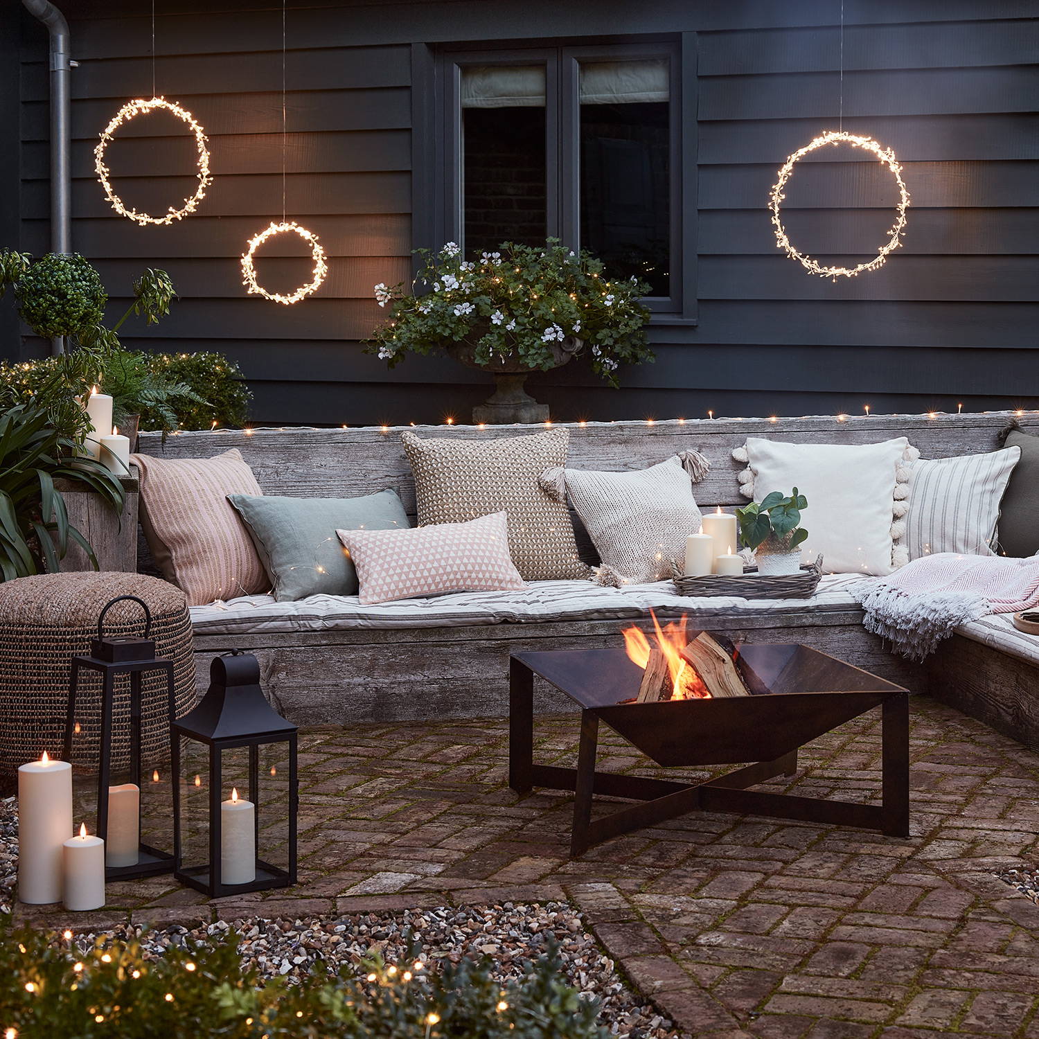 A summer seating area with a firepit, LED candles, lanterns and starburst lights creating a cosy setting. 