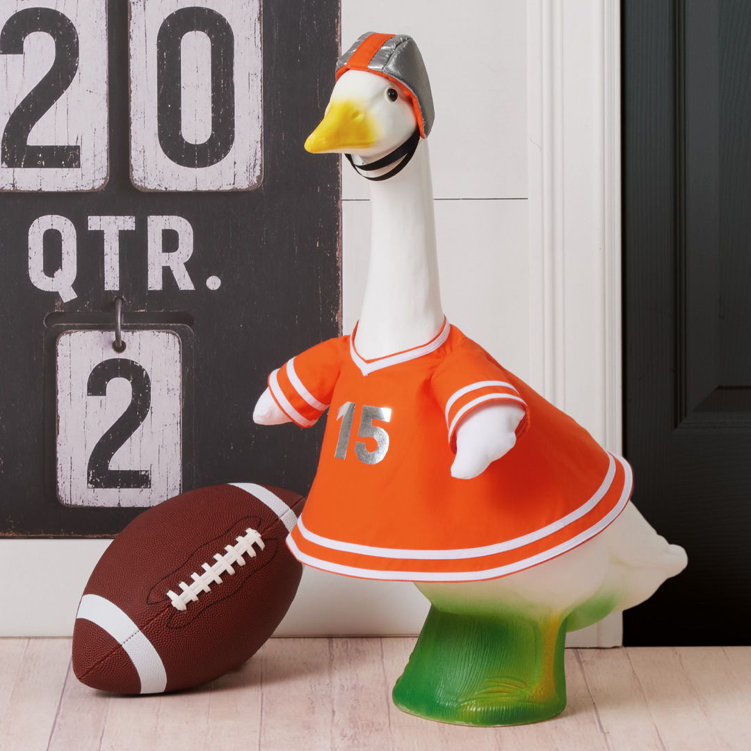 A decorative goose wearing an orange football jersey next to a football.