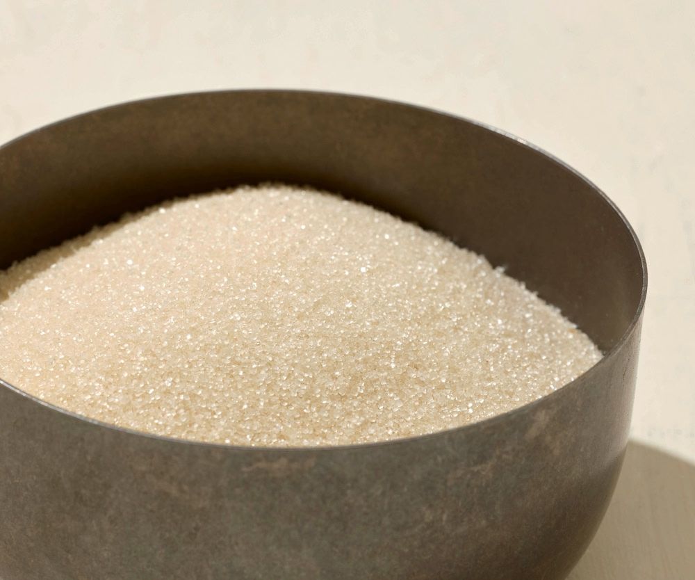 A bowl filled with granulated white sugar.