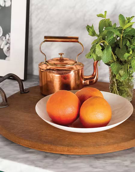 copper teapot with bowl of oranges