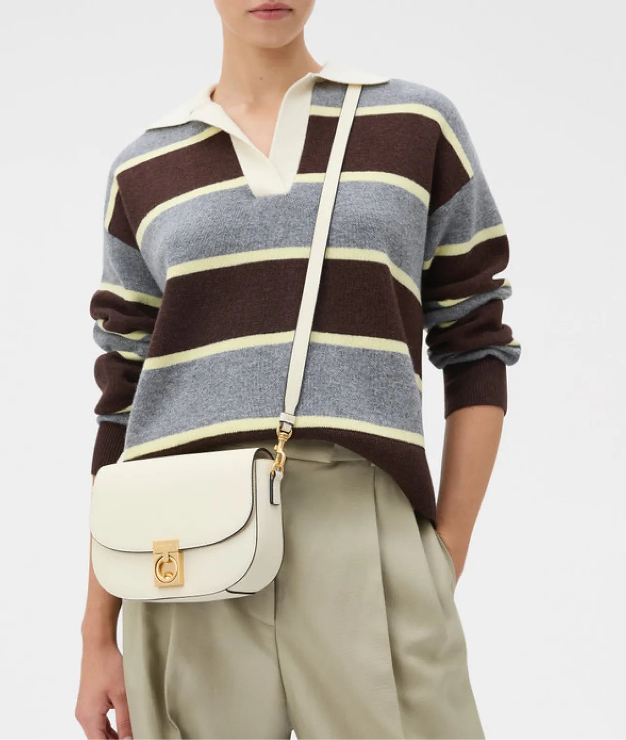 Person wearing a striped sweater and holding a small crossbody bag.