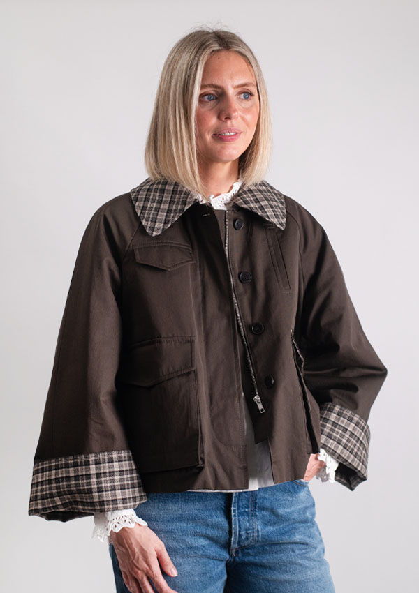 Lottie wearing a brown jacket with plaid collar and sleeves, smiling.