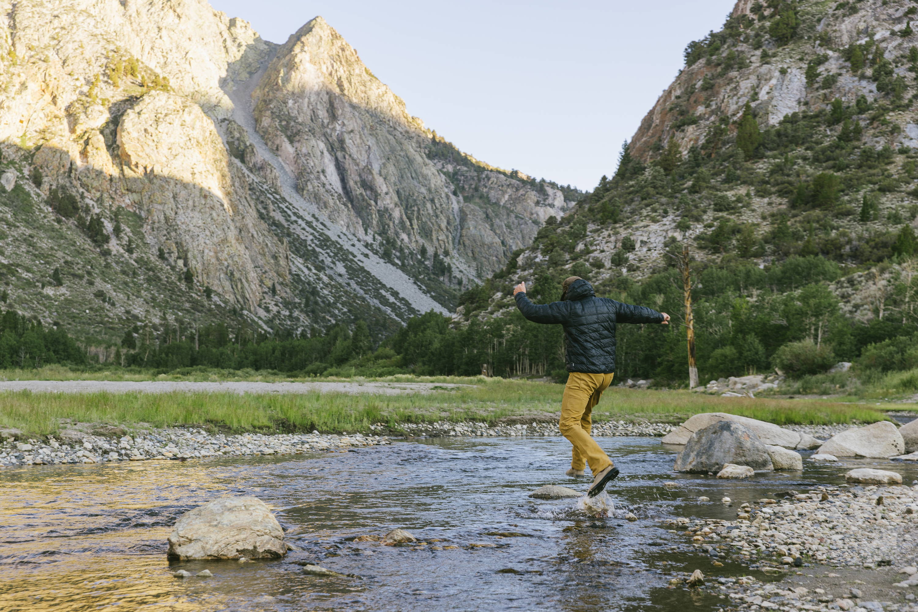 Man jumping across river in Cast Iron Sierra Pant