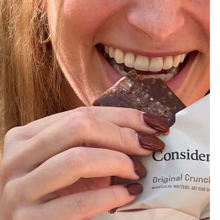 A woman biting into a Consider This low histamine protien bar