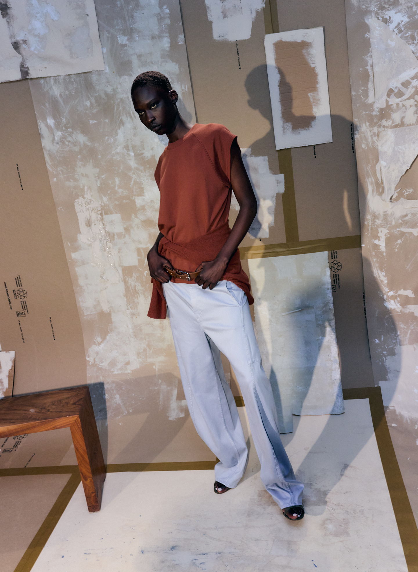 Model in stylish outfit posing against a textured background.