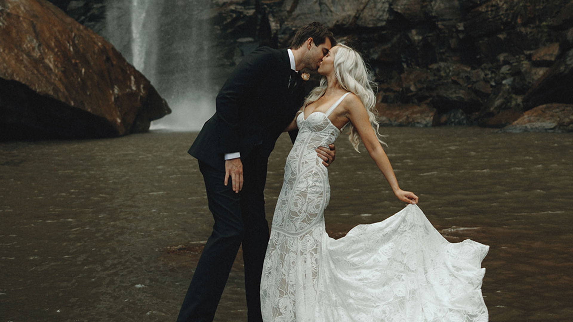 Thomas and Tiffany sharing a kiss in front of a waterfall