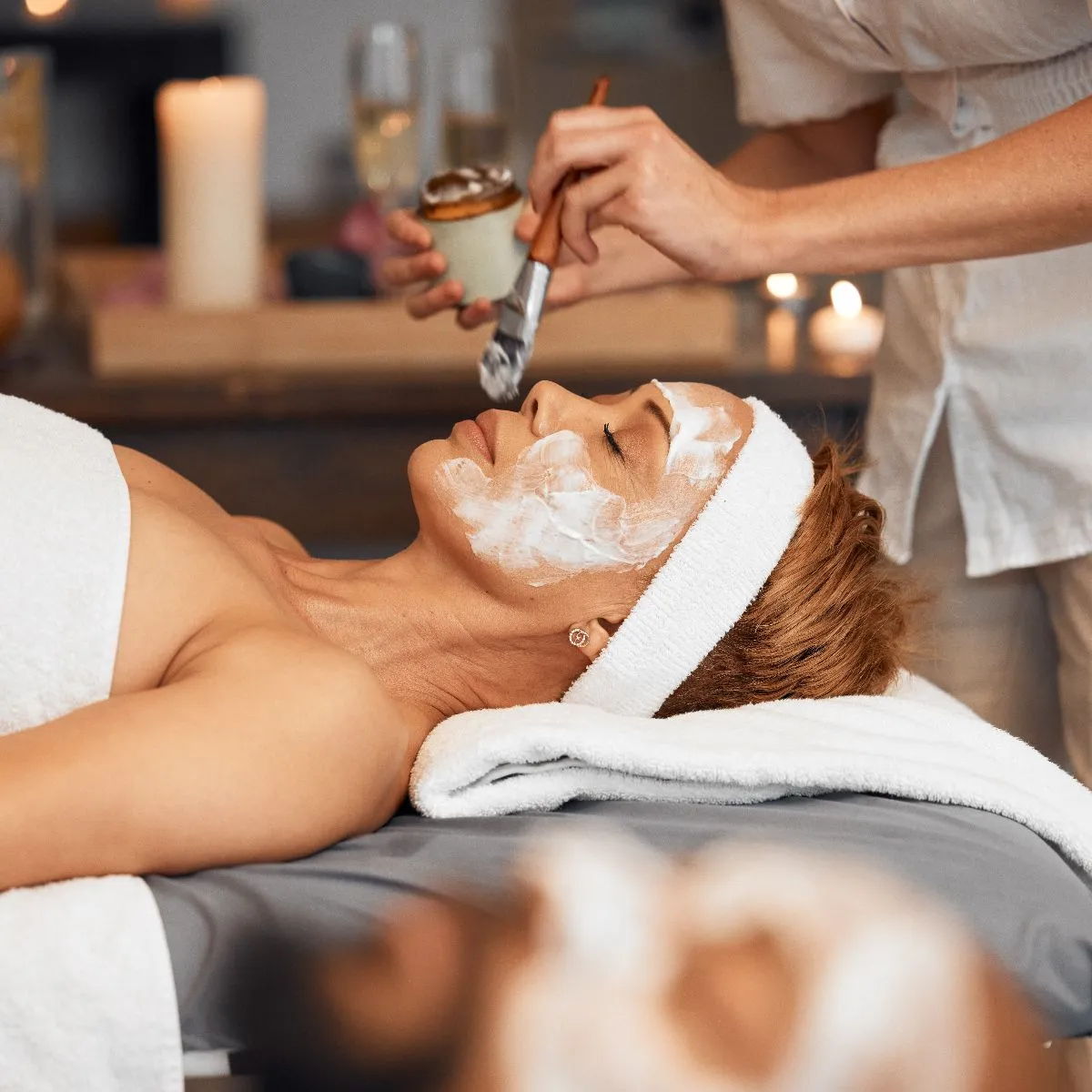 A woman receives a facial treatment in a spa setting.