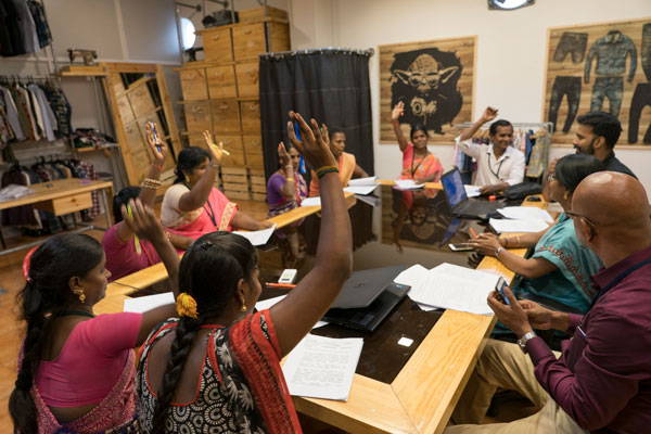 Group of Fair Trade workers sitting at table voting.