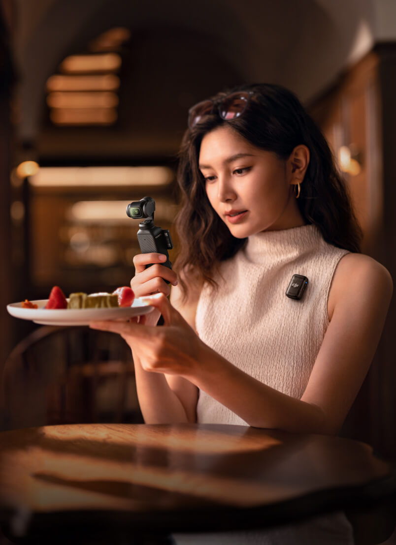 Woman holding a plate of food while taking a photo with an Osmo Pocket 3