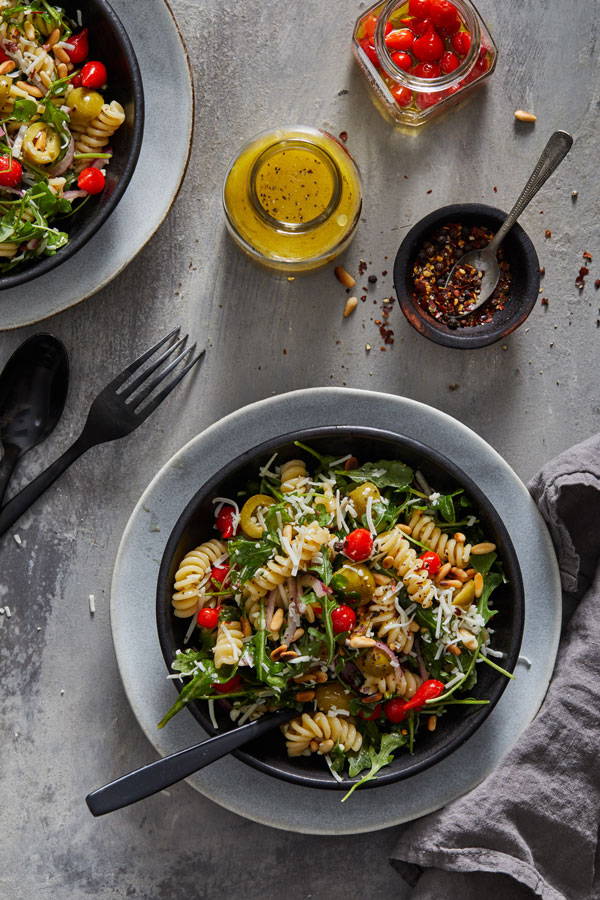 Fusilli pasta salad with tangy pepper drops, arugula and olives