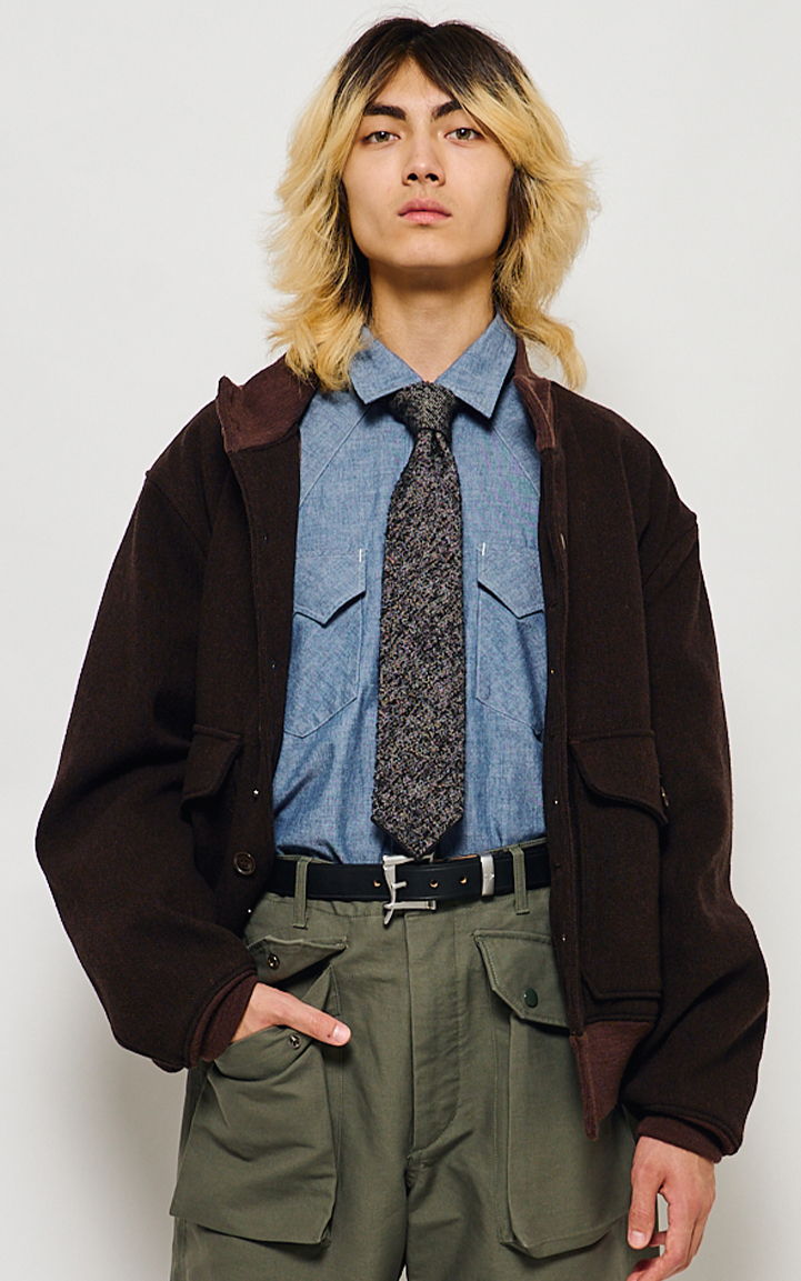 A person with long hair wearing a jacket, shirt, and tie.