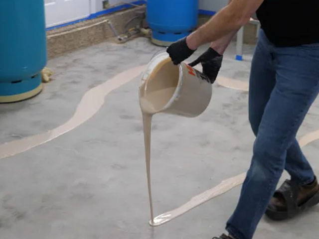 Spreading thin, even coat of Moisture Seal Epoxy Primer on floor using a magic trowel squeegee and microfiber roller.