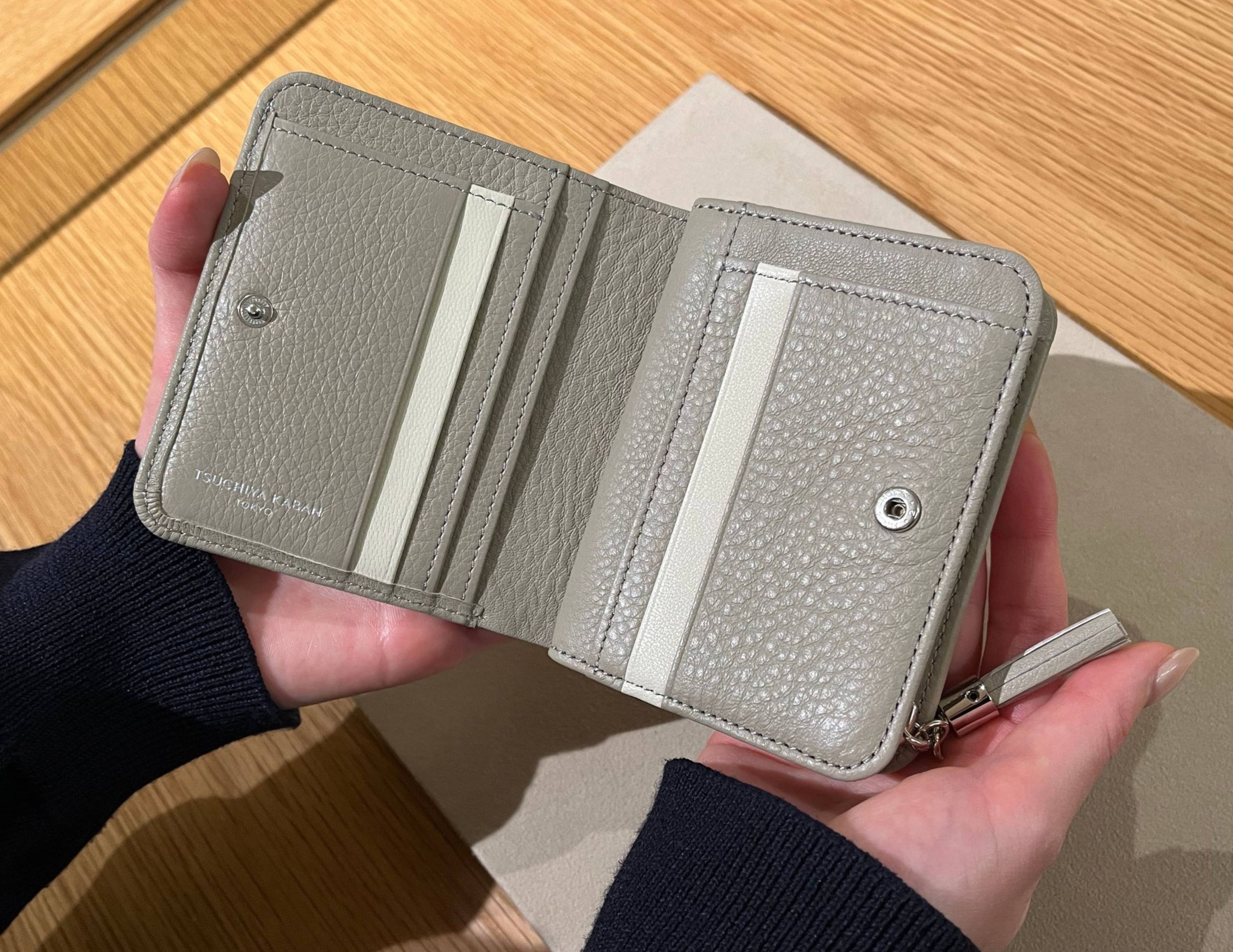 A person holding an open gray wallet with card slots.