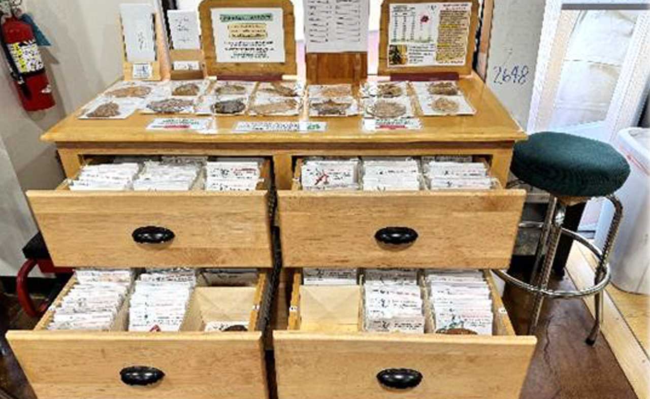 Wooden display with drawers containing various items and informational signs.