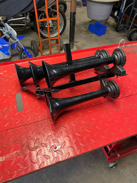 Black Conductor's Special 244K train horn bells on red tool bench in garage before install on Stephen's 2018 Silverado 1500 photo 2
