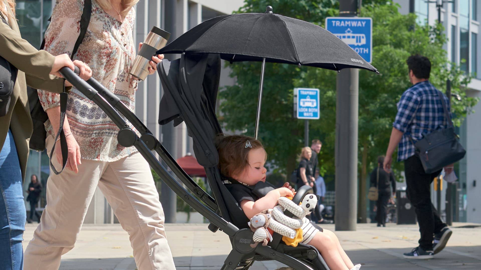 Little girl sat in a pushchair with a parasol attached