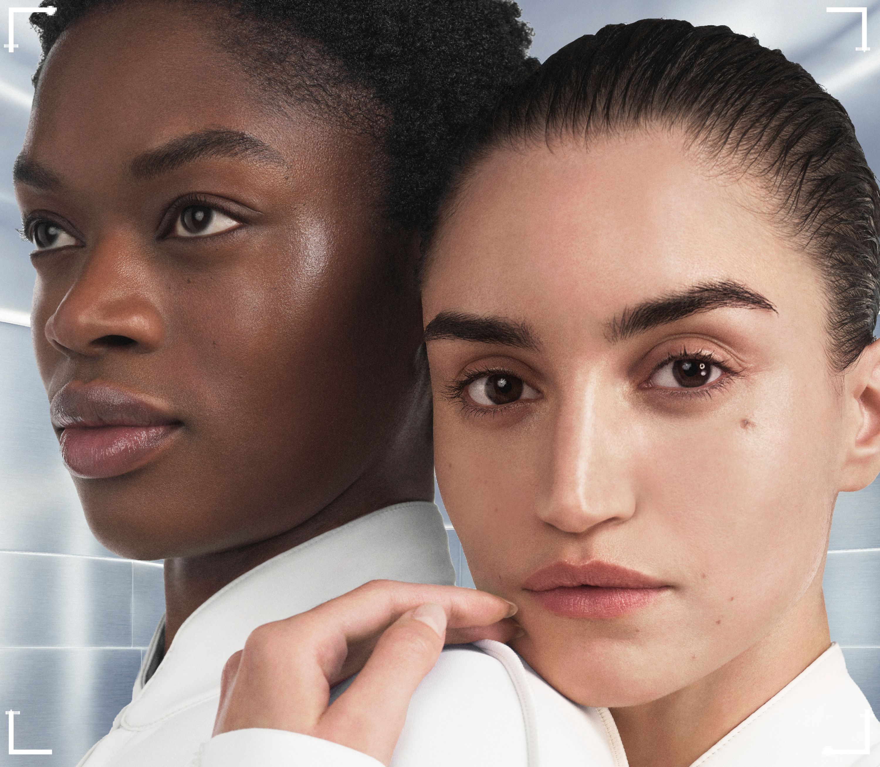 Two women with diverse features posing together against a light background.