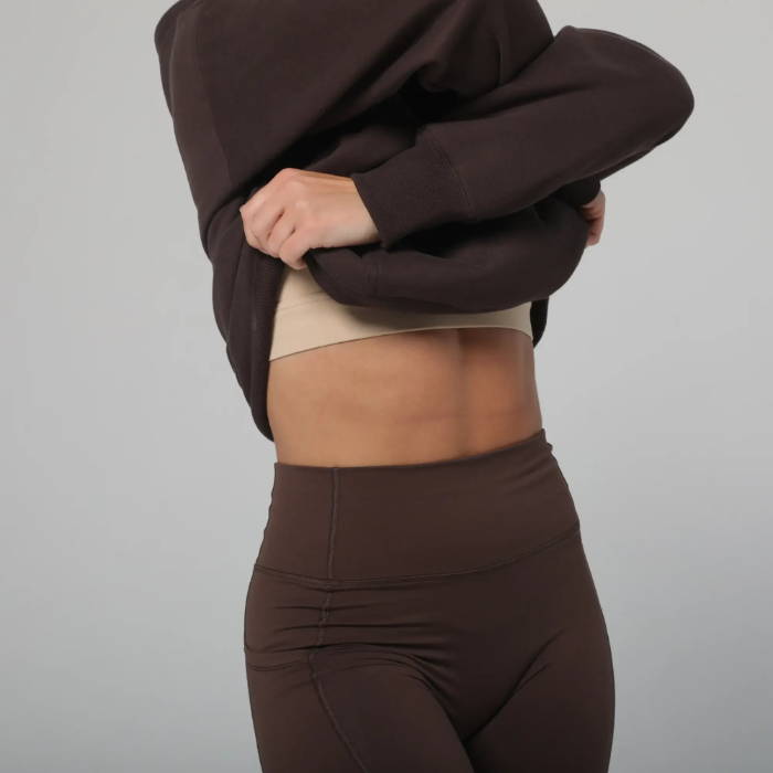 female model wearing brown sacre clothes lifting hoodie up