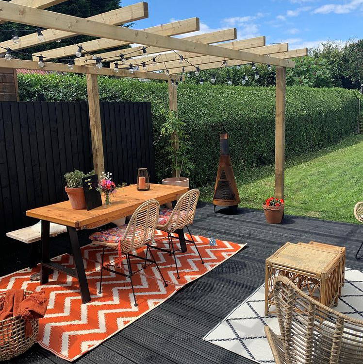 Decking space in garden with festoons hung from pergola above dining table