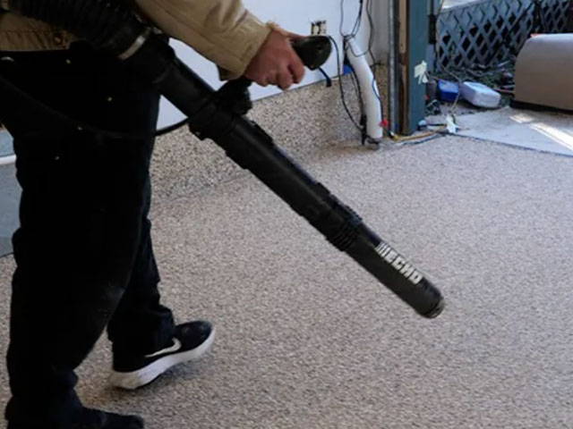 Scraping the dried epoxy floor lightly in a cross-hatch pattern, removing loose flakes for a smooth finish.