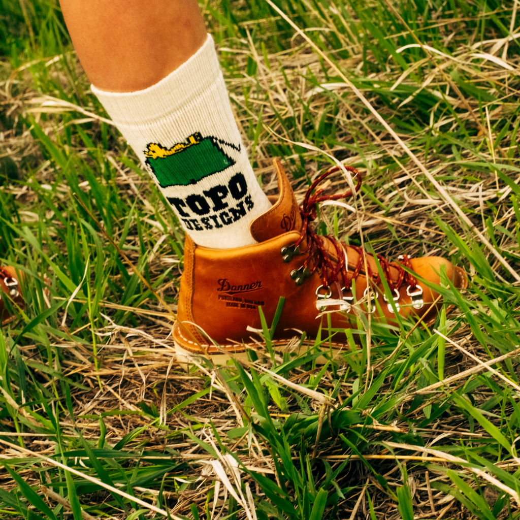 A foot wearing a brown boot and white sock in grass.