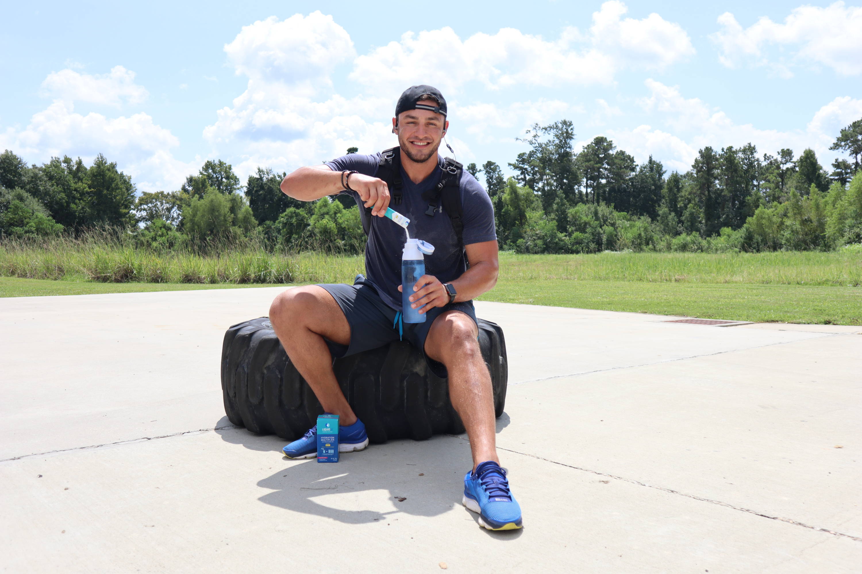 Athlete pours Liquid IV into water bottle after training session.