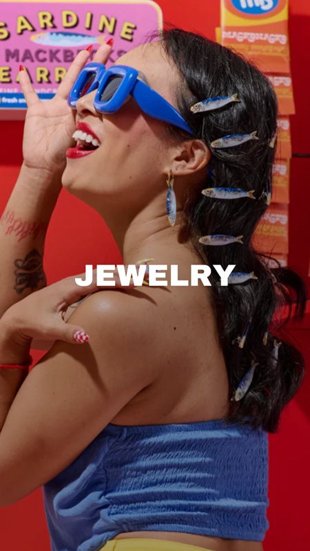 Person with sunglasses and jewelry, posing against a colorful background.