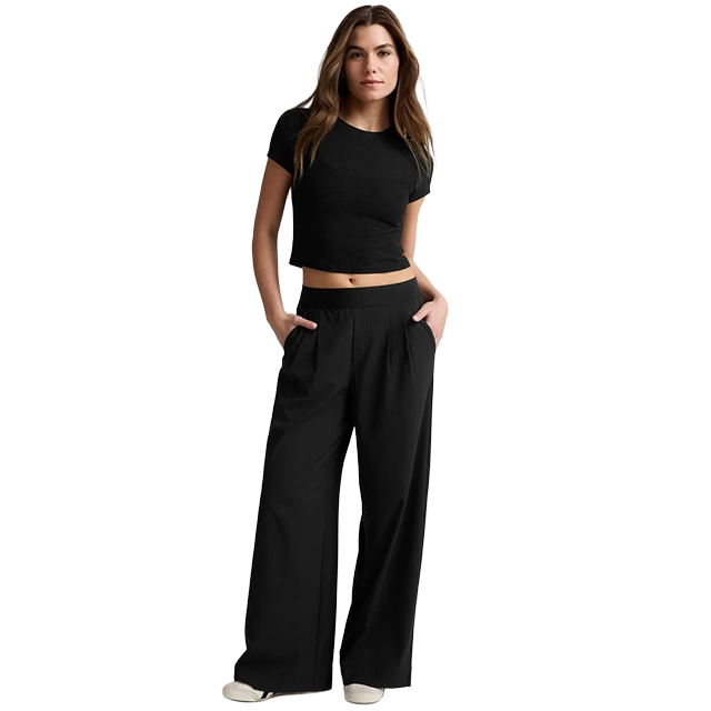 A young woman wearing a black crop top and wide-leg pants.
