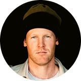 A man with a serious expression wearing a beanie and a light jacket.