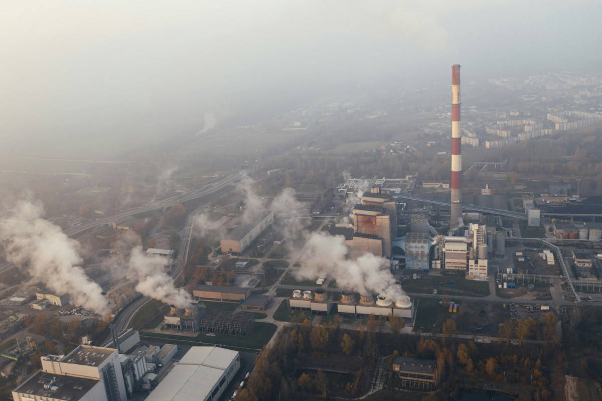 A city with fossil fuel plants spewing smoke into smoggy skies