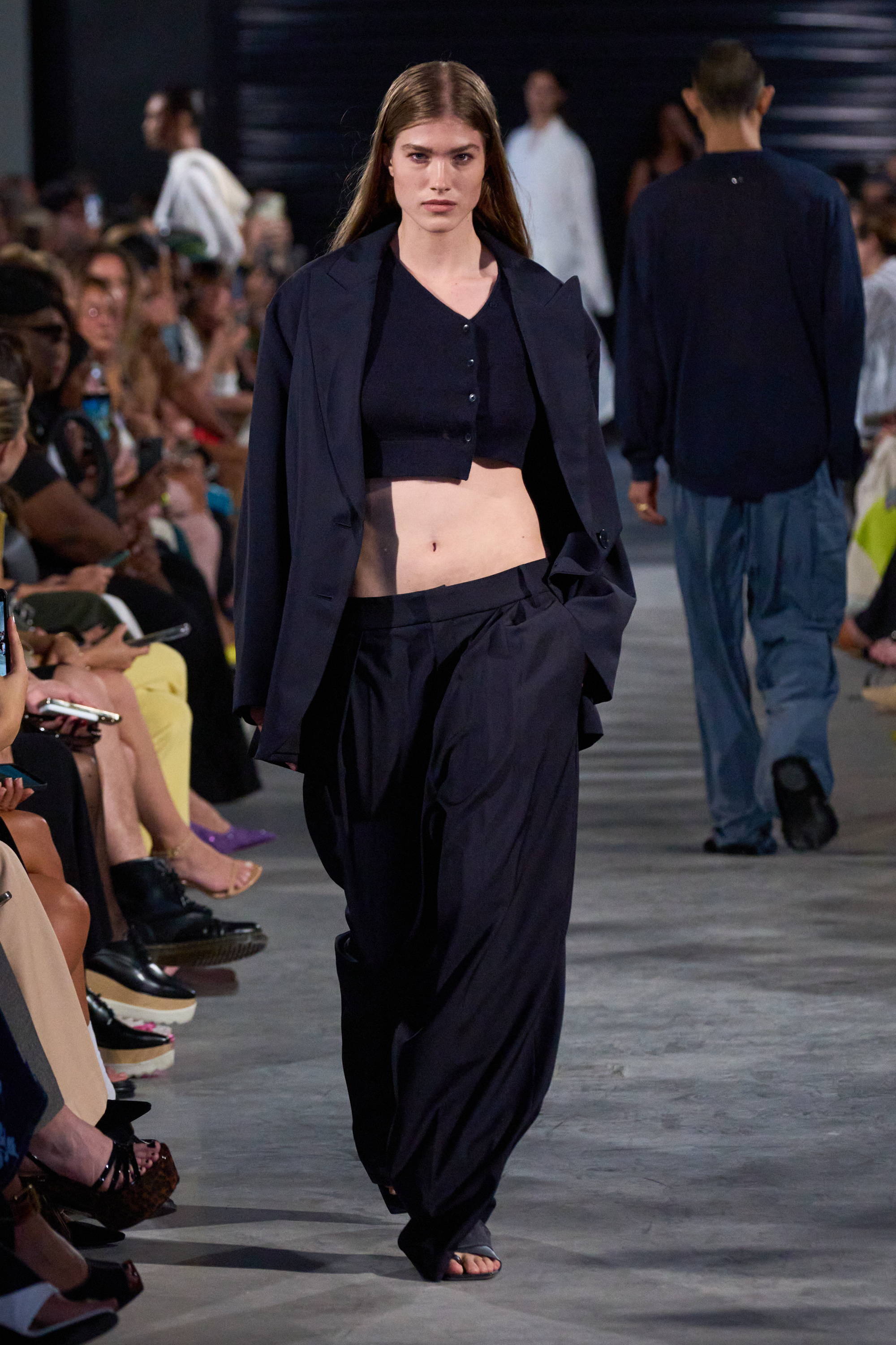 Model on a runway wearing blazer, cropped sweater, and pants