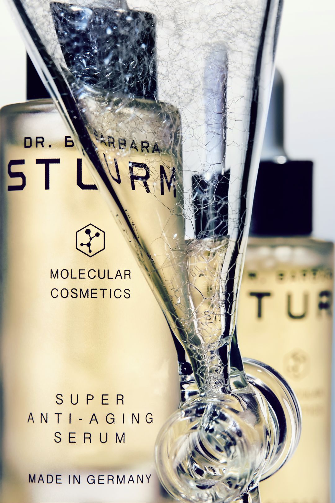 Bottles of Dr. Barbara Sturm skincare products with a champagne glass.