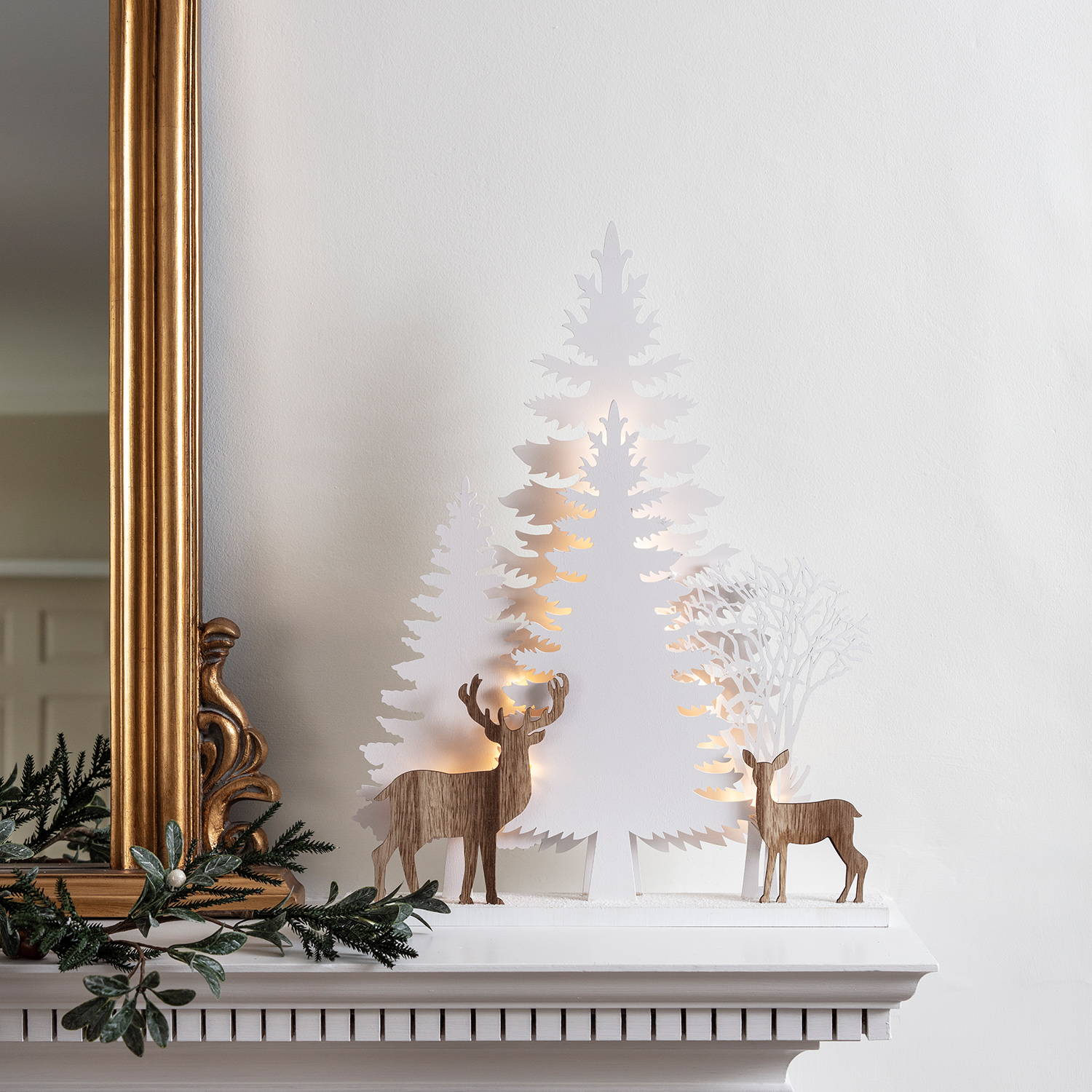 Reindeer silhouette Christmas window light featuring white Christmas trees and wooden reindeer illuminated with a warm glow 