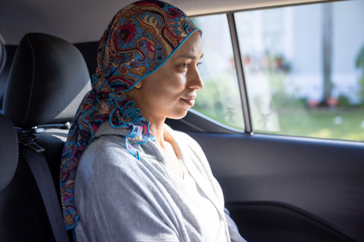 Woman wearing a colorful scarf, gazing out of a car window.