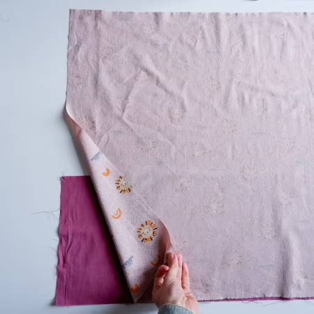 larger piece of fabric positioned on the magenta fabric strip to make a pillowcase
