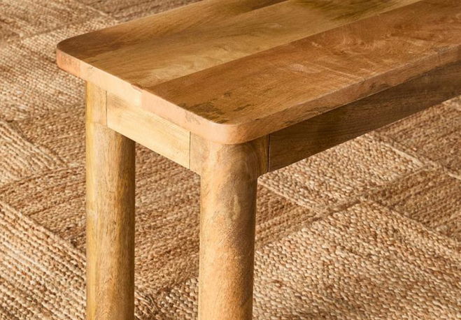 Wooden table with a smooth surface and sturdy legs on a textured floor.