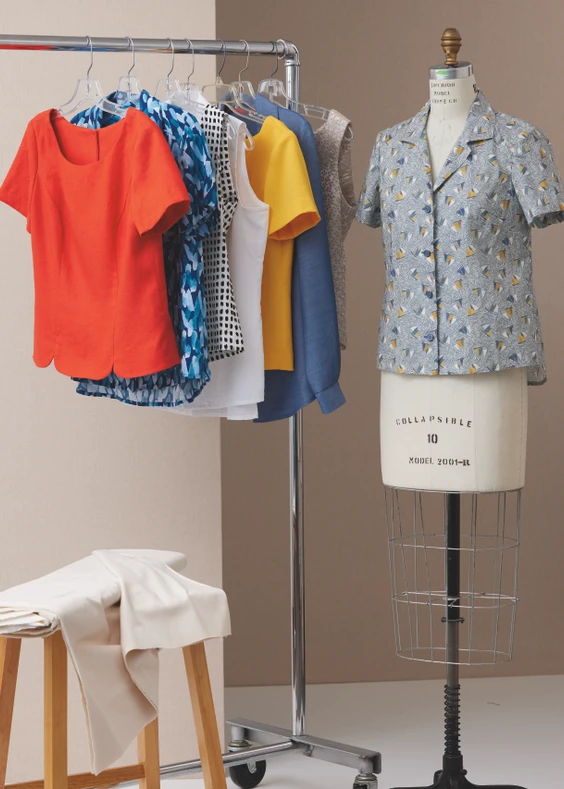 Clothing on a rack next to a dress form and fabric.