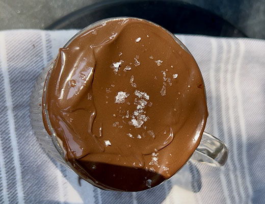 A glass jar filled with chocolate dessert on a striped napkin.