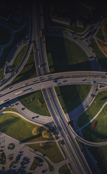 Aerial view of a complex highway interchange with vehicles and greenery.