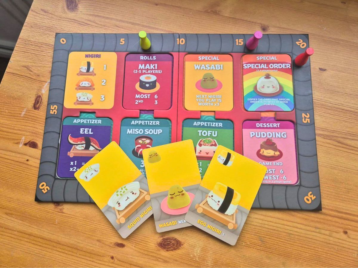 Board game setup with cards and player pieces on a wooden table.
