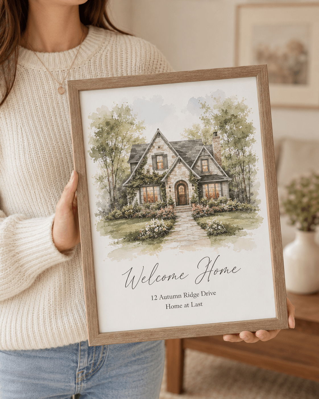 Woman holding a framed illustration of a house with 