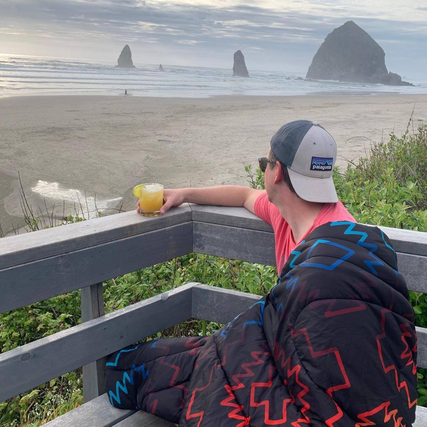 Man drinking margarita at Cannon Beach with Rumpl beach blanket