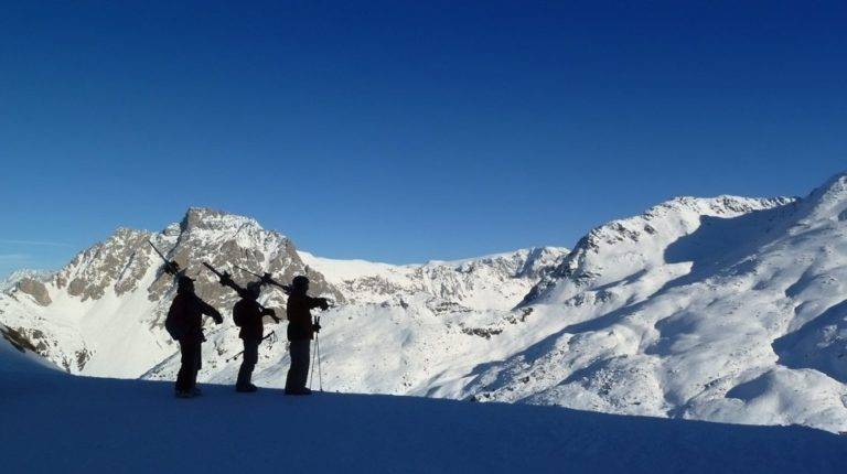 A group of skiers look over a mountain ridge.