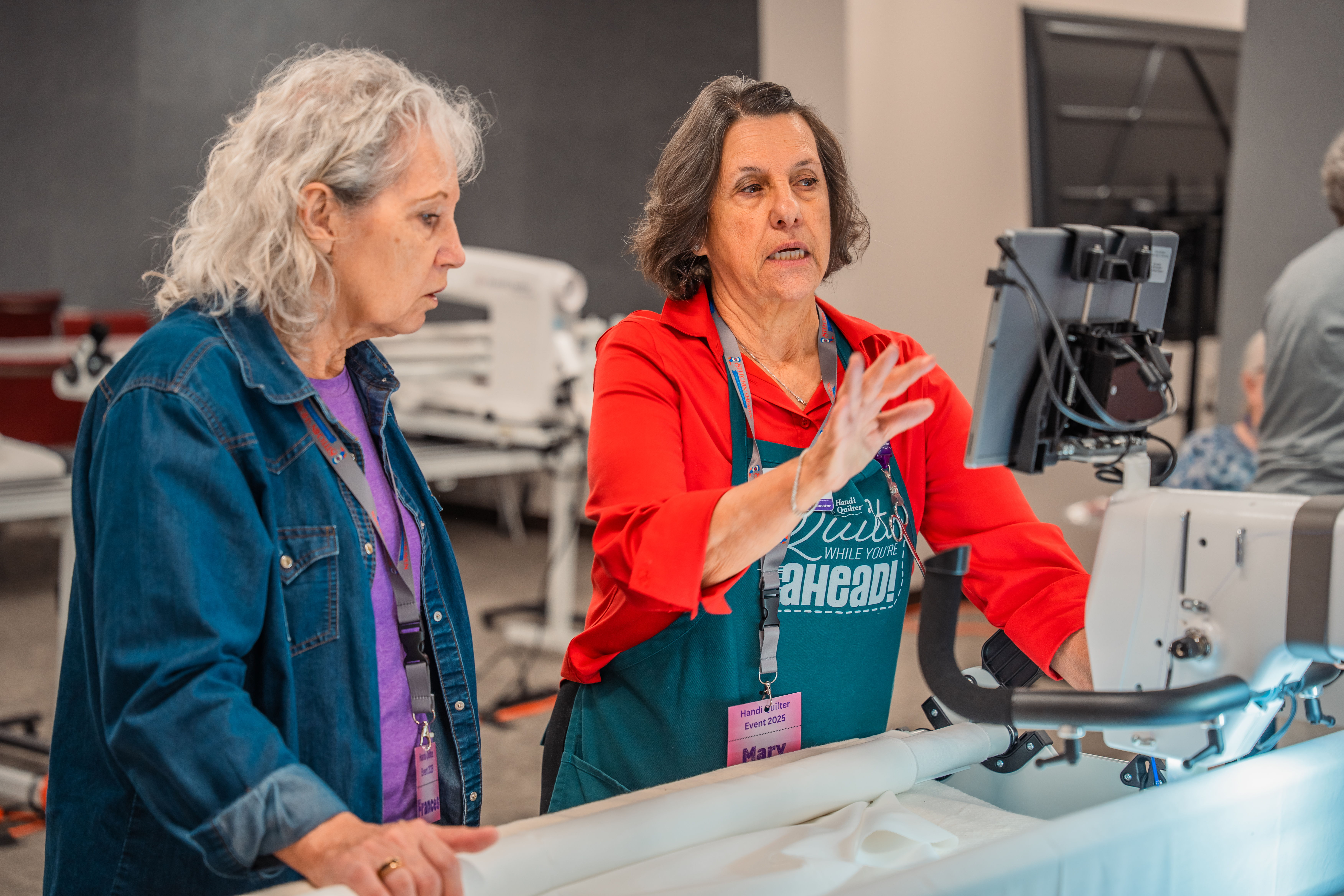 Two women discussing sewing techniques at a workshop.