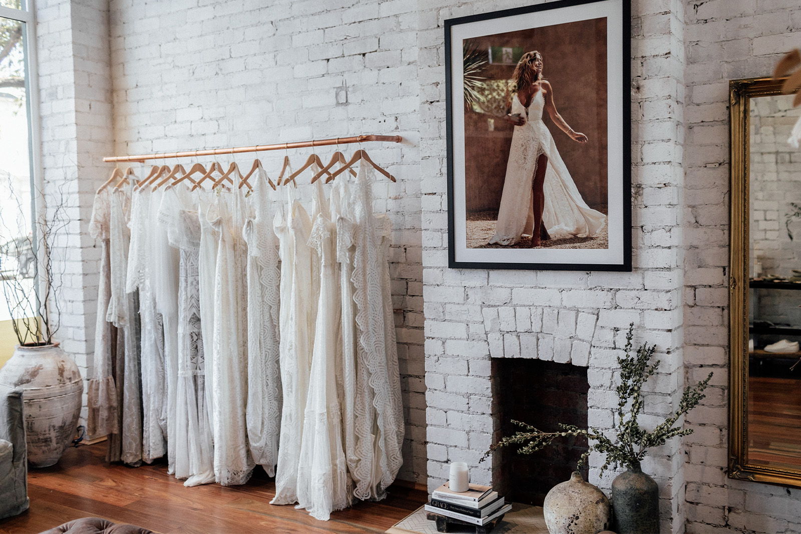 A boutique interior featuring white dresses, a framed photo, and a mirror.