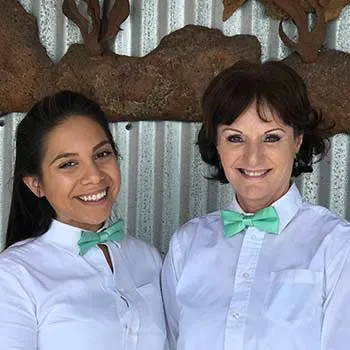 Two waiters wearing a seafoam bow tie.