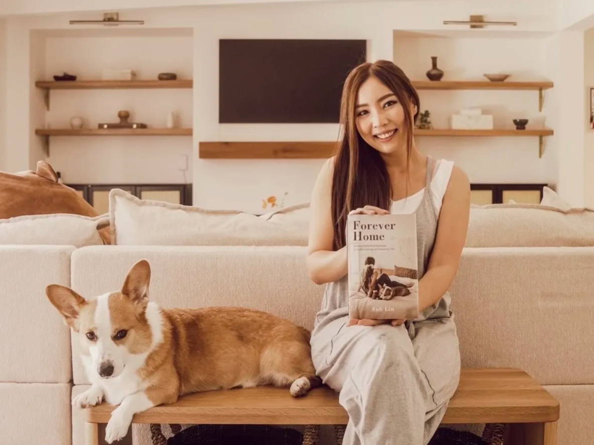 Anh Lin sitting next to her dog, holding a copy of Forever Home