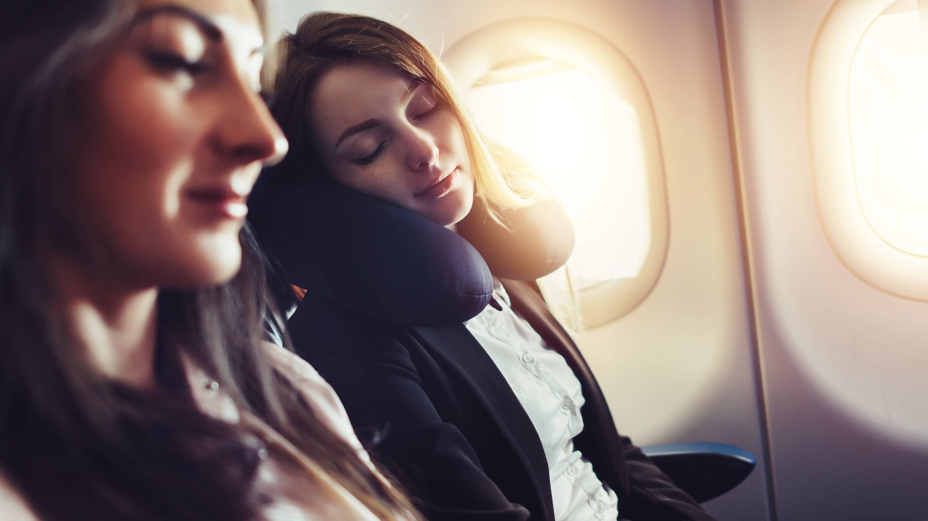 Woman sleeping with neck pillow in an airplane
