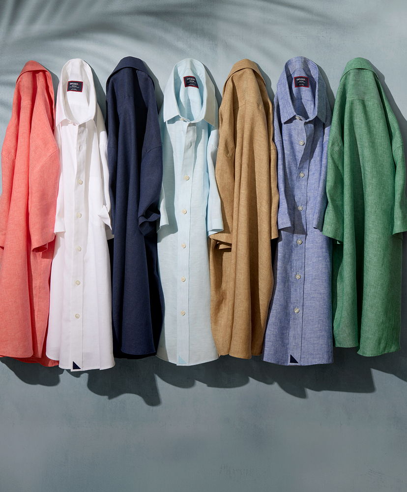 A row of colorful shirts hanging against a textured background.