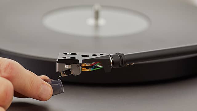 Close-up of a turntable cartridge being handled.